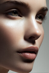 Fototapeta premium Young woman's face, close up profile showing hydrated skin, subtle make up, and illuminated features for beauty