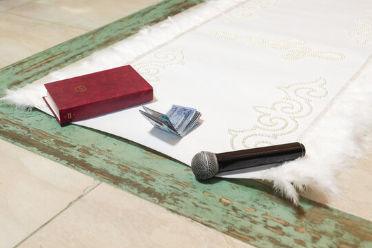 Microphone book and Kazakhstan tenge cash on white carpet with pearl ornaments
