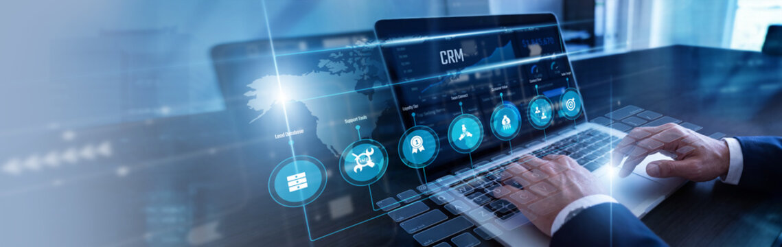 Sales executive managing client leads using laptop updating enterprise CRM databases on a bright virtual screen dashboard. Modern customer relationship management and business communication.