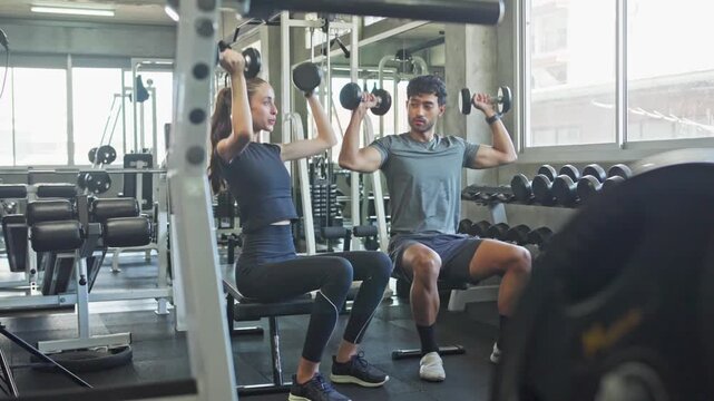 Pair working out together in a contemporary fitness center using weights and various exercise machines