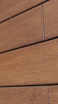 Vertical video. Close-up of modern house facade with yellow wood-look tiles outdoors.