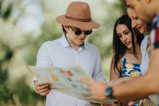 A group of young friends studies a paper map outdoors. They examine the map together as they plan a casual summer outing.