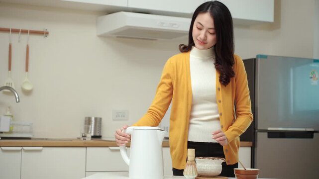 Pretty young woman making traditional green tea matcha using bamboo natural whisk mixing beverage for healthy drink with antioxidant nutrition in wellness routine and modern healthy lifestyle.
