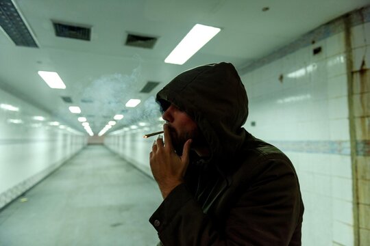 Hooded man smoking in an empty underground tunnel