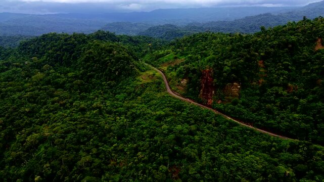 Aerial View of Winding Mountain Road Through Tropical Rainforest in Ecuador, Green Hills, Remote Jungle Route, Cloudy Sky and Andean Amazon Travel Scene