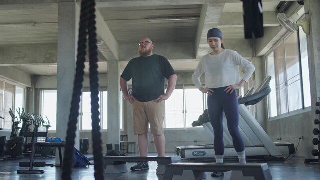 Two fitness lovers participating in an energetic workout session inside a contemporary gym setting