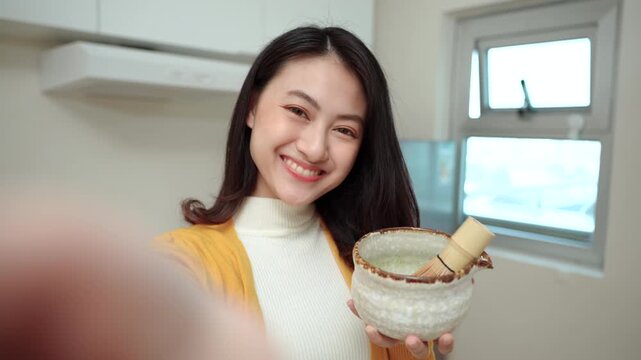 Woman creating live social media with smartphone looking at camera while promoting Japanese matcha tea in live commerce, creator or influencer marketing on healthy beverage and modern online business.