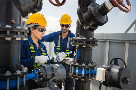 Engineers inspecting cooling equipment and water pump at industrial plant, Professional technician and worker team performing maintenance on industrial HVAC and piping system on a commercial rooftop