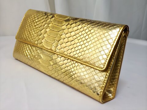 Golden snakeskin clutch bag for luxury fashion and festive holiday marketing.