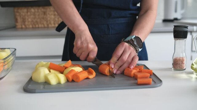 Woman Cutting A Raw Carrot In A Close-Up On The Kitchen
