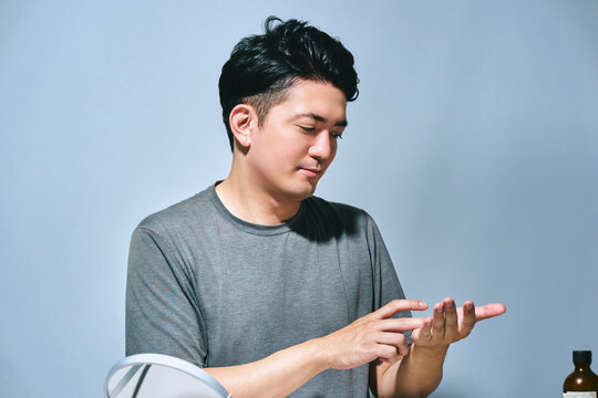 手のひらの美容液を確認する30代の日本人男性のアンチエイジングやメンズスキンケアイメージ