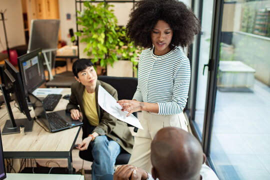 Team leader presenting document to colleagues in modern office