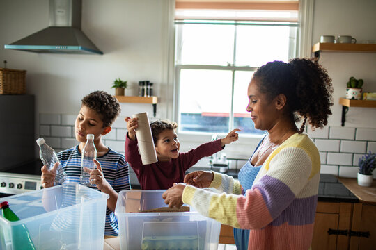 Mother and children recycling together in home kitchen
