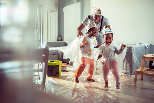 Father with two children playing during home painting in living room
