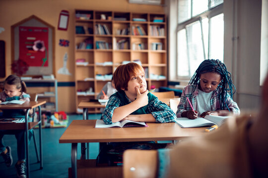 Elementary students studying and thinking in classroom
