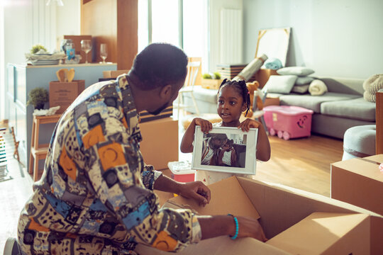 Father and daughter unpacking boxes in new home living room
