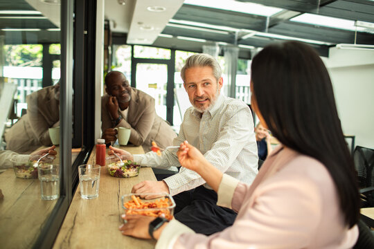 Coworkers eating lunch and chatting in office break area