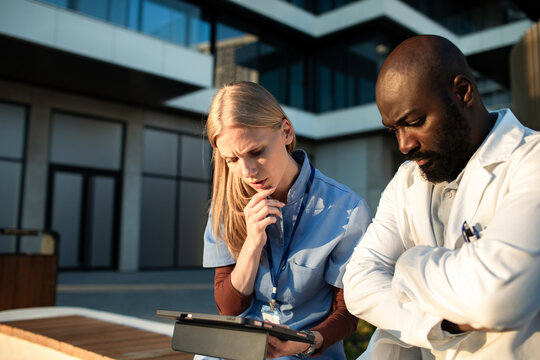 Doctors reviewing patient data on tablet outside hospital