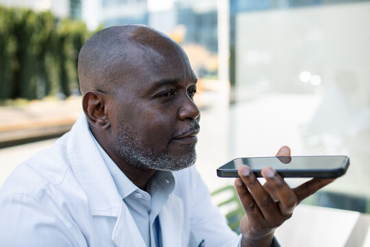 Senior doctor using smartphone voice command outdoors