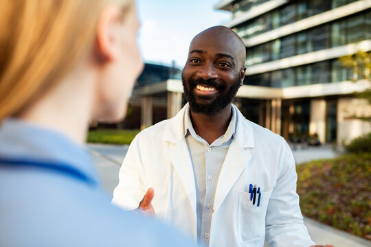 Smiling doctor talking with colleague outside hospital
