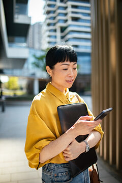 Businesswoman using smartphone on modern city street