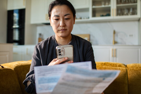 Woman checking bills on smartphone at home