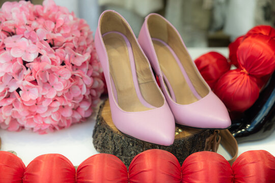 Elegant pink high heel shoes on wooden display with hydrangea flowers