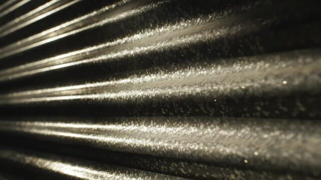 Close-up of a textured surface with parallel lines, the material illuminated by sunlight casting shadows