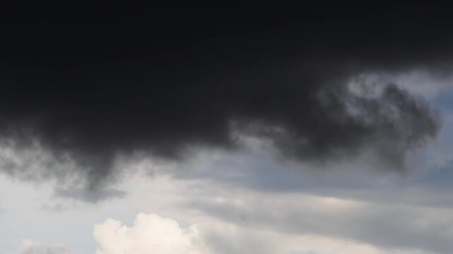 Ominous, swirling black clouds against a gray sky&mdash;a dramatic darkness associated with rain or a storm.