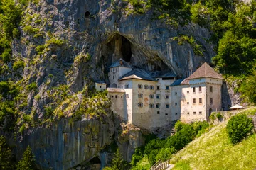 Predjama castle built in a cave in Slovenia. Popular tourist attraction and historic monument in an idyllic valley near Postojna Caves on a summer day. Wide angle scenery and major sight. © ON-Photography