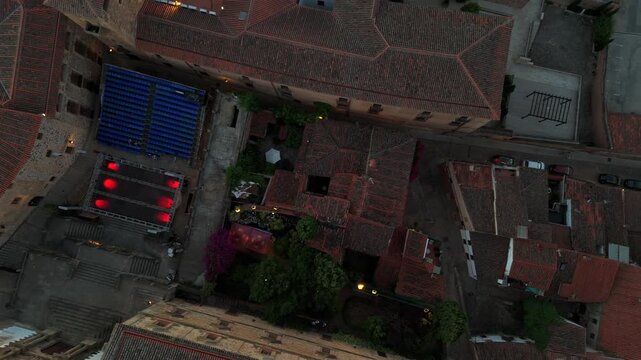 Vertical top down drone shot directly above the historic center of a medieval Spanish city showing rooftops courtyards and narrow streets.