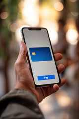 Fototapeta premium A man's hand holding a mobile phone with a digital credit card and money sign on the screen, an online payment interface.