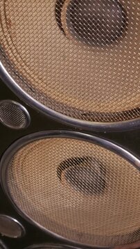 A vintage audio speaker cone sits behind a protective metallic mesh grill in extreme close up. Concept of retro music playback, acoustic technology, and nostalgic sound system culture.