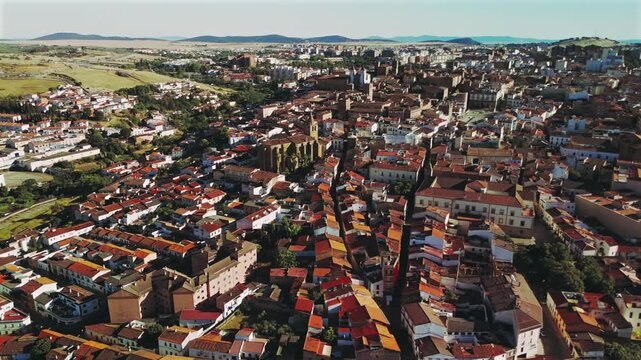 Wide aerial panorama over a medieval Spanish town with terracotta rooftops surrounded by rolling countryside and open landscape.