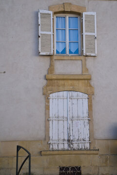 Vertical view of a house facade with shutters and sandstone.