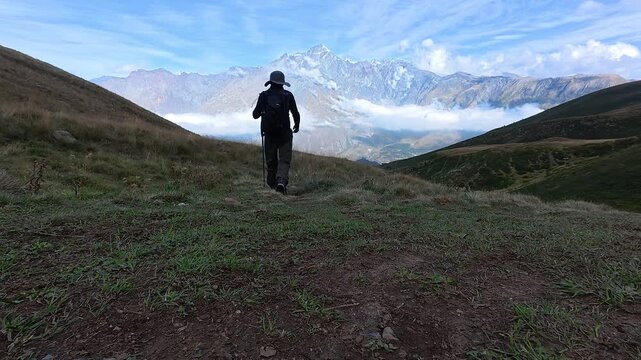 4k video of a hiker from behind walking down a mountain toward scenic peaks in Georgia.