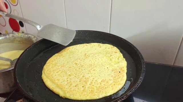 Close-up of Flipping Yellow Besan Chilla or Dosa on a Non-Stick Pan in Indian Kitchen