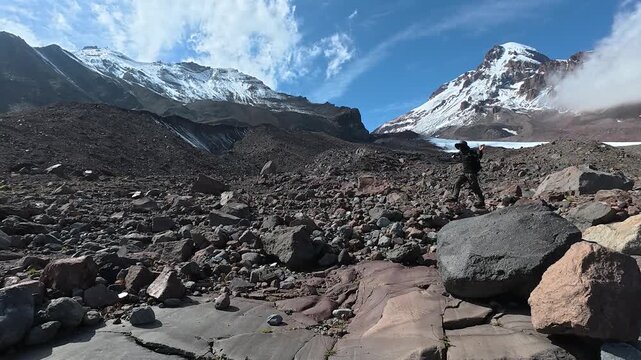 4k video of a hiker walking on a rocky glacier moraine toward Mount Kazbegi, Georgia.