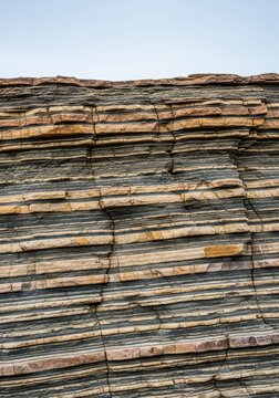 Detailed close-up view of ancient geological rock layers showing distinct stratification, earthy texture, and natural erosion patterns, beige, earth, deep