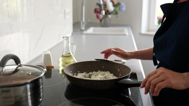 Close-Up Of Woman Pouring Oil Into Pan With Onions