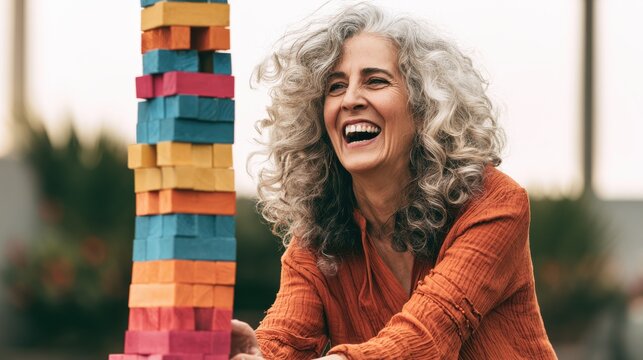 Smiling woman laughing while playing a block stacking game outdoors