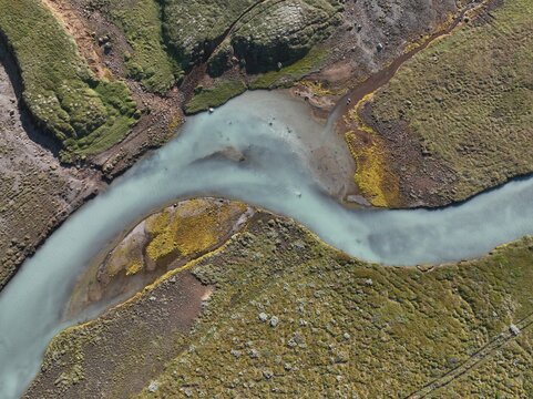Aerial view of a glacial river winding through the mossy volcanic landscape in Hella, Rangarthing ytra, Iceland.