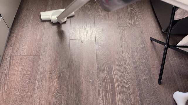Vacuum cleaner head moving on wood floor cleaning dust