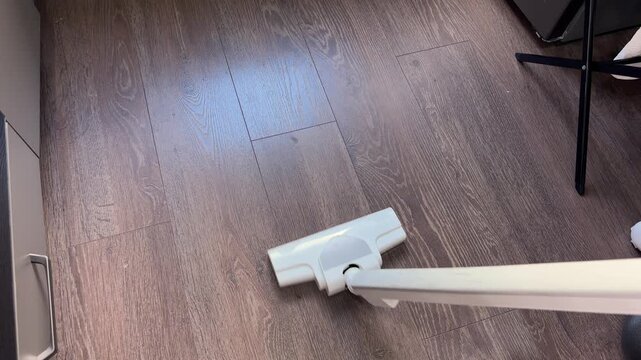 Vacuum cleaner head moving on wood floor cleaning dust
