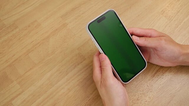 Swipe Gesture on Smartphone with Green Screen Display on Wooden Table