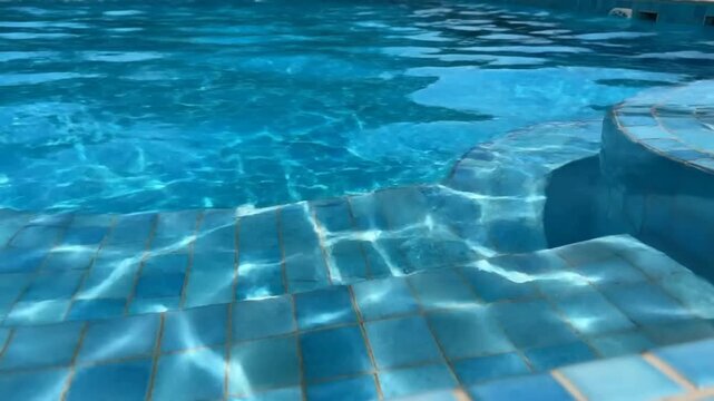 Shimmering Sunlight Reflecting on Blue Tiled Swimming Pool Water