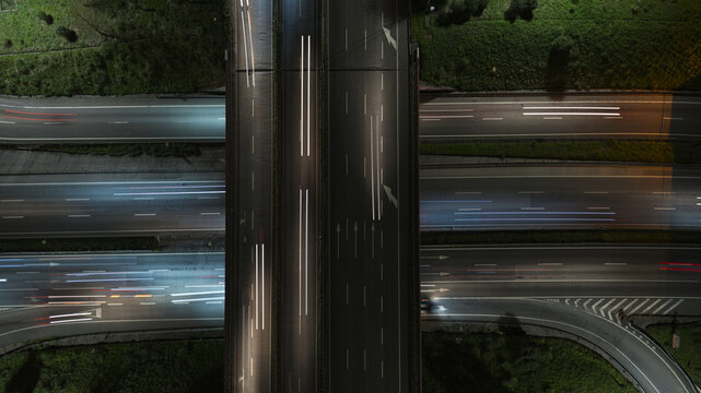 Aerial view of highway intersections at night with long exposure light trails from moving cars during rush hour in Porto, Portugal.