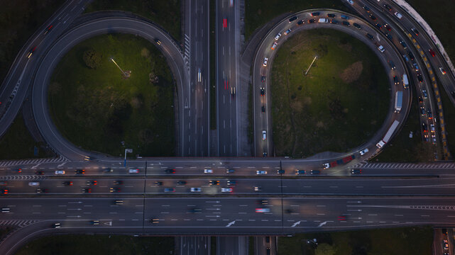 Aerial view of highway intersections at night with long exposure light trails from moving cars during rush hour in Porto, Portugal.
