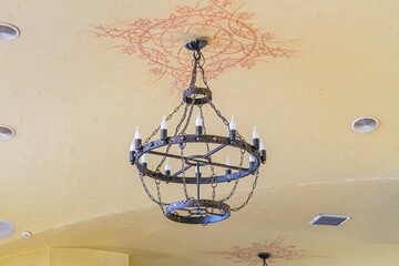 Obraz premium Chandelier with multiple arms, circular light pattern on floral ceiling design, beige and cream walls, soft lighting, cozy ambiance