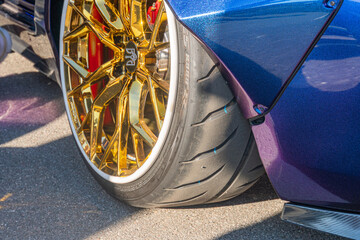Naklejka premium Close-up view of a purple Mazda Miata, side angle towards the rear wheels with gold F1-branded high-performance tires on carbon fiber bodywork, under soft natural li Kyiv, Ukraine September 21, 2025